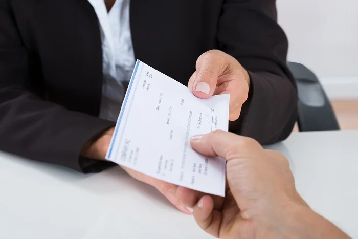 Cheque siendo entregado sobre un escritorio