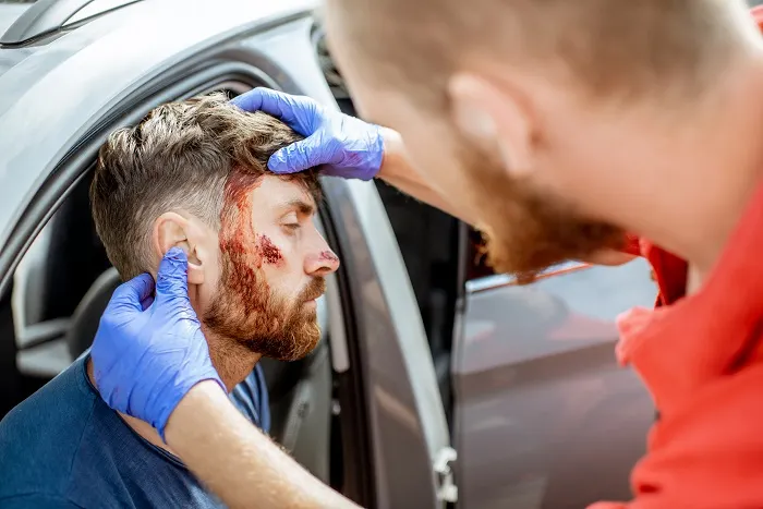 Medic checking a driver's head wound after a car crash
